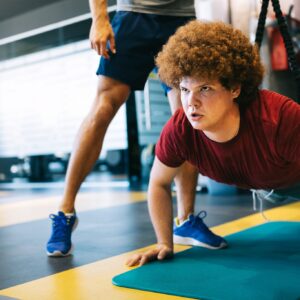 トレーナーとジムでエクササイズす男性