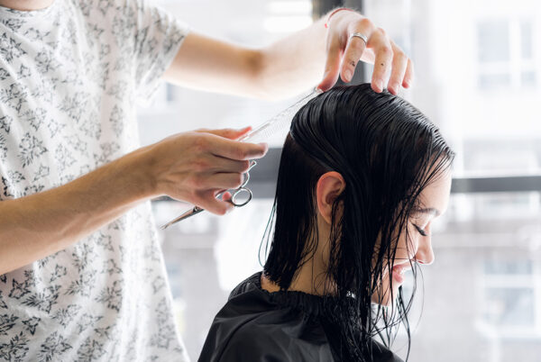 美容師がヘアサロンで女性の髪を切る