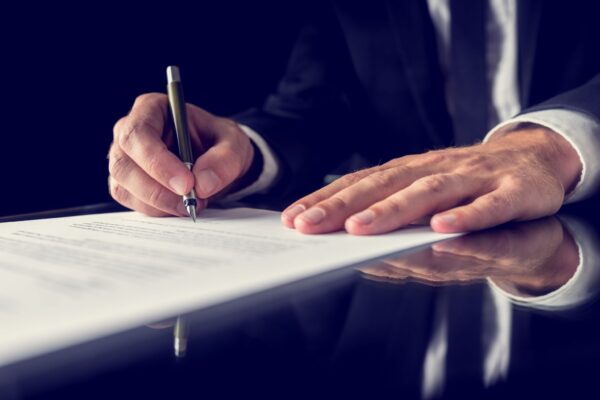法的文書に署名するスーツ姿の男