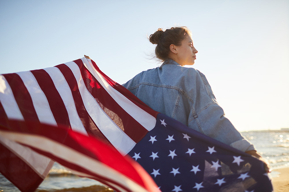 ビーチで国旗を手にアメリカを思う