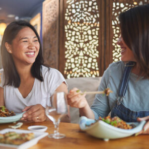 アジア人女性二人がアジア料理を楽しんでいる写真