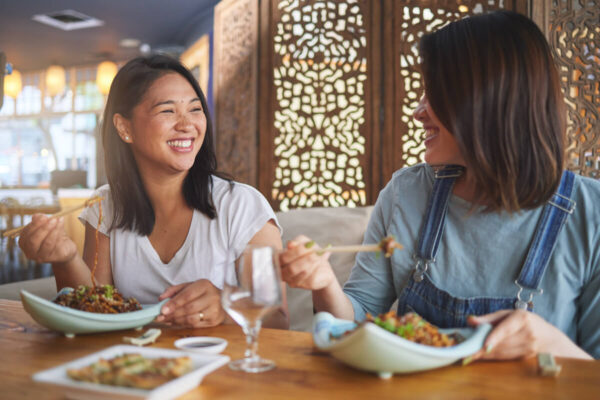 アジア人女性二人がアジア料理を楽しんでいる写真