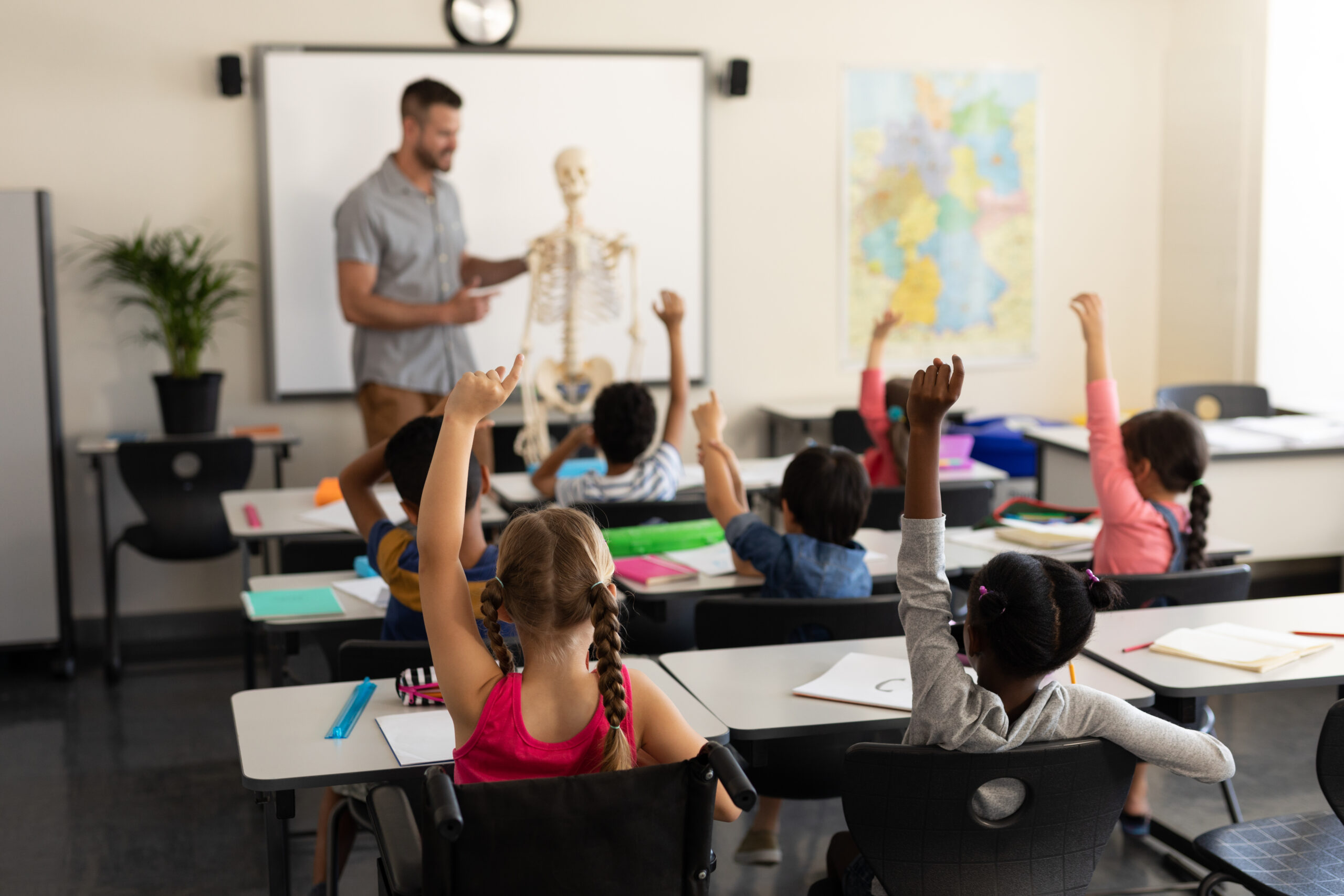 教室で子供たちが挙手をしている。