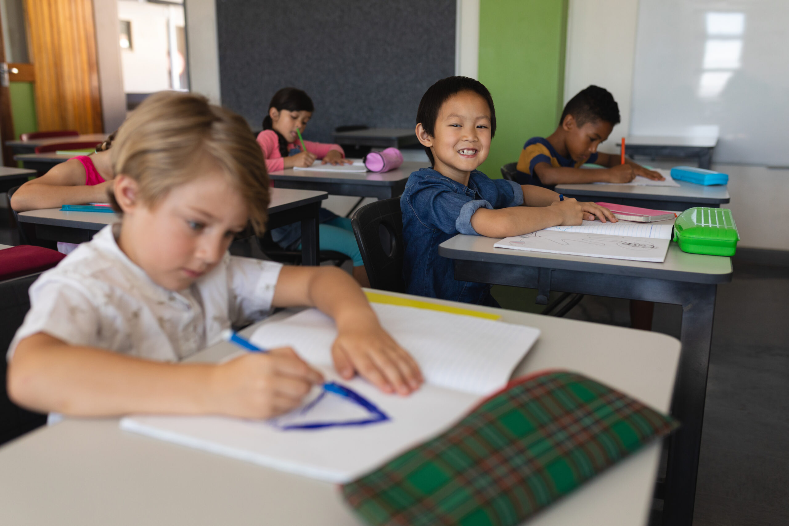 学校で子供が机に向かって絵を描いている。