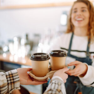 カフェで店員がお客様にお持ち帰りのコーヒーを渡している